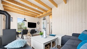 Un salon chaleureux avec une cheminée, un téléviseur et des fauteuils confortables.