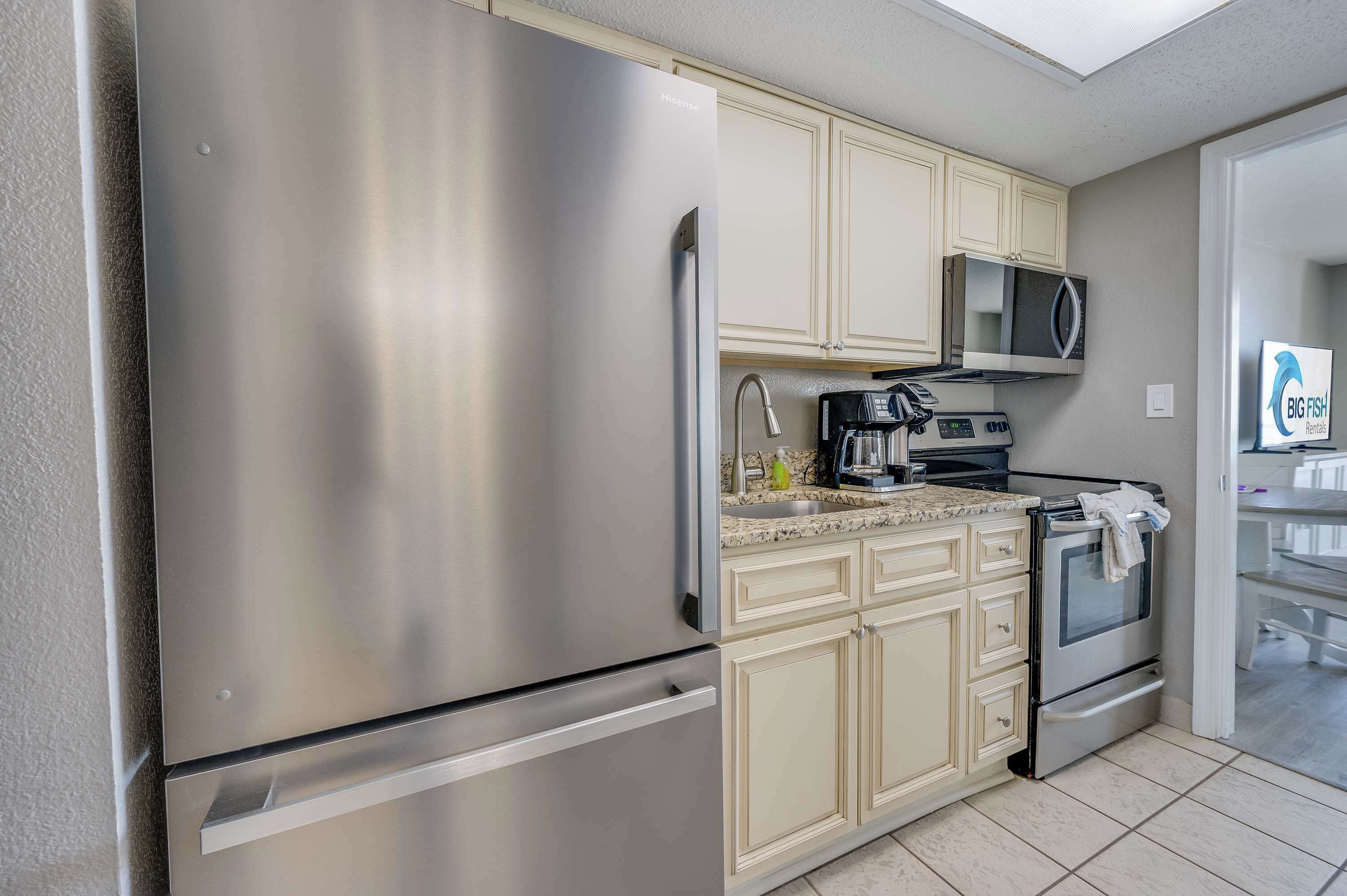 A modern kitchen with stainless steel appliances, including a refrigerator, microwave, and oven.