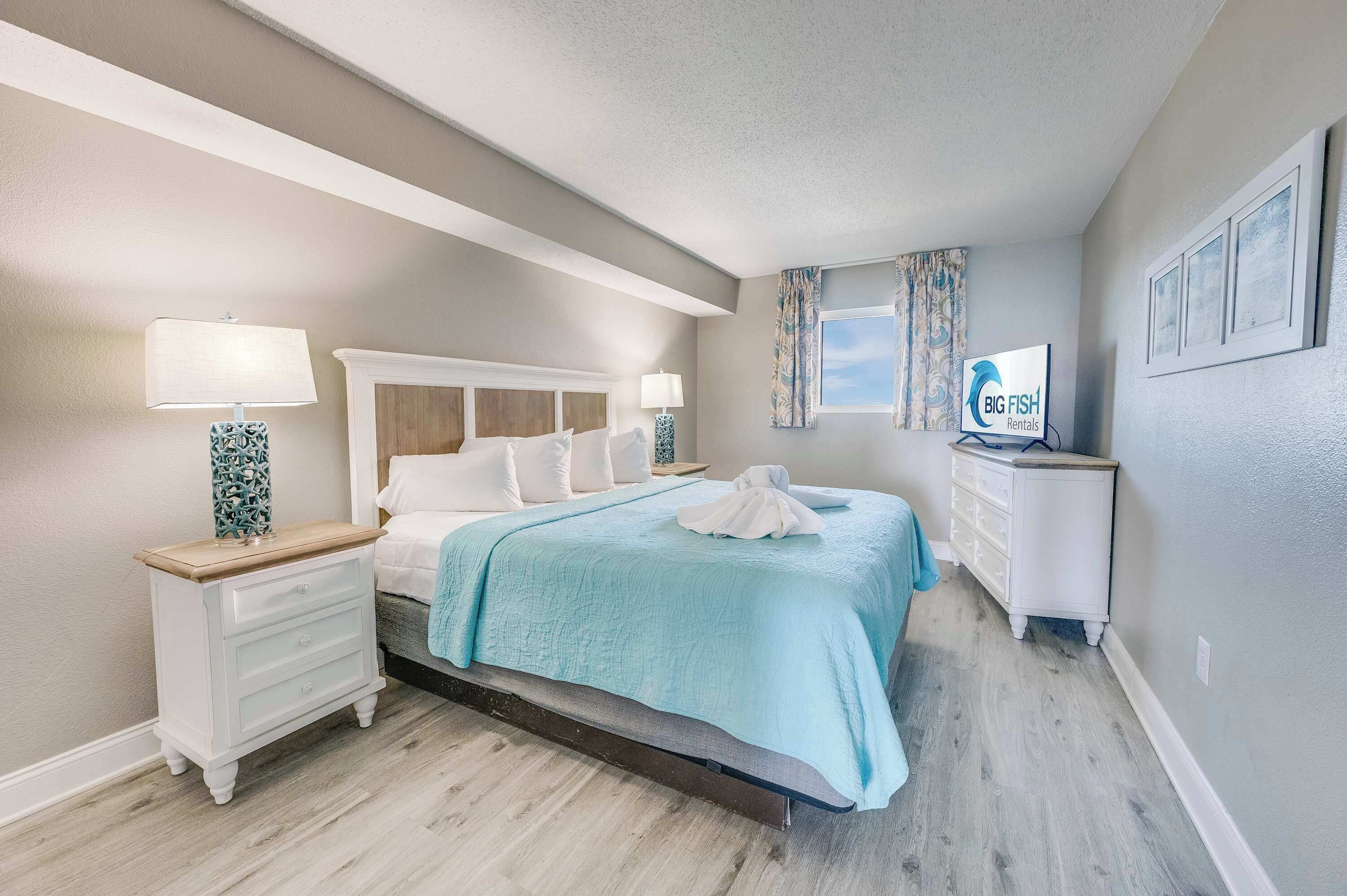 Une chambre à coucher comprenant un lit, des tables de chevet, une commode et un téléviseur.