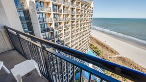 Un hôtel de grande hauteur doté de nombreux balcons donnant sur une plage et une piscine.