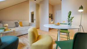 Una sala de estar moderna con un sofá, sillas, una mesa redonda con una lámpara y una planta.