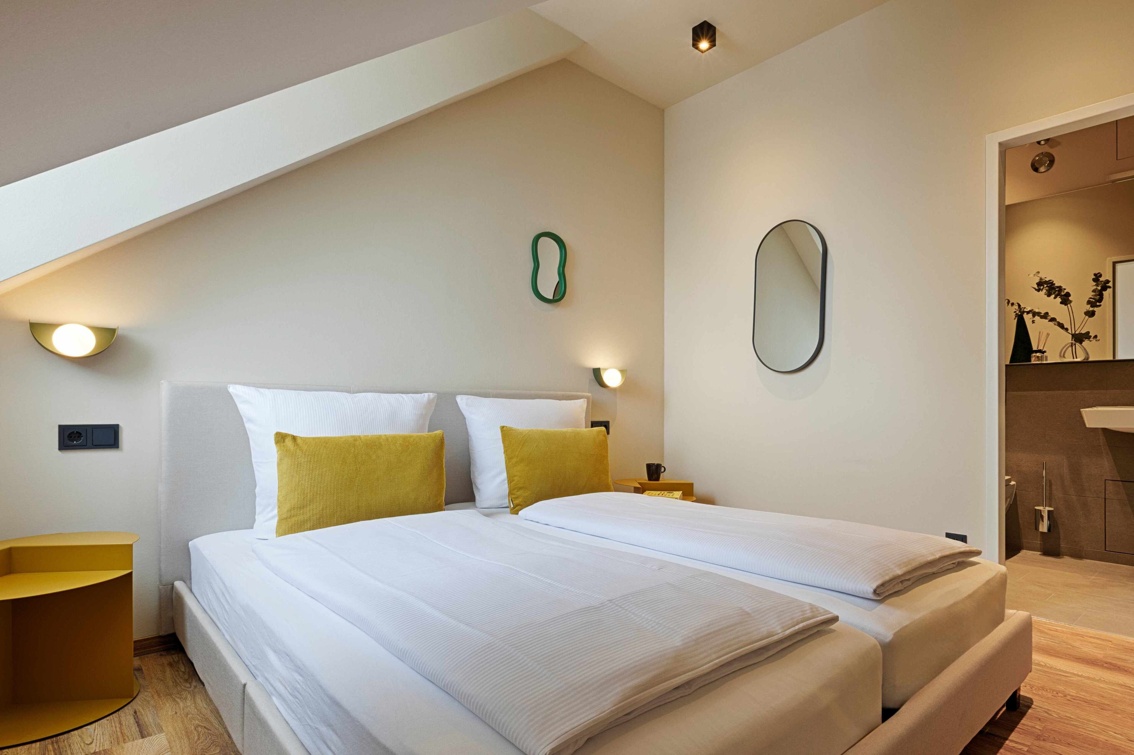 Ein modernes Hotelzimmer mit einem großen Bett, zwei Nachttischen und einer kleinen Sitzecke.