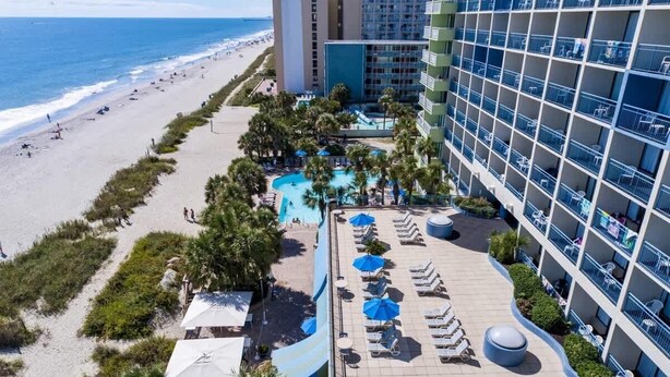 Un complexe hôtelier doté d’une piscine, de chaises longues et offrant une vue sur la plage.
