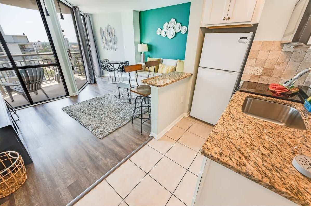 A modern kitchen with a granite countertop, a built-in sink, and a refrigerator.