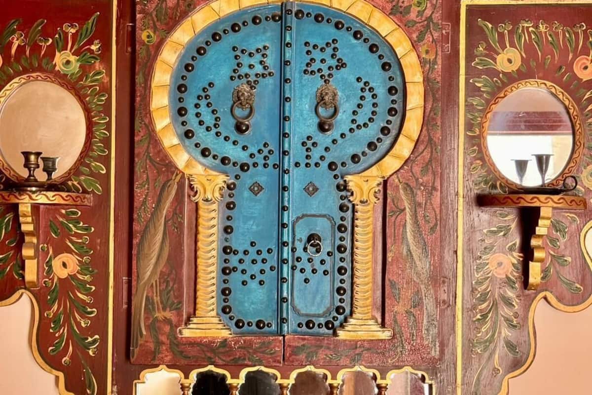 Uma porta de madeira detalhada com esculturas elaboradas e dois espelhos.