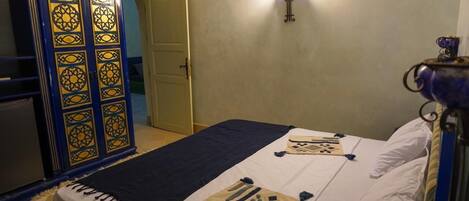 A bedroom with a bed, a wardrobe, and a wall-mounted light fixture.