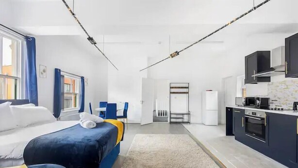 Une chambre d’hôtel moderne équipée d’un lit, d’un bureau, d’une kitchenette et d’une salle de bain.