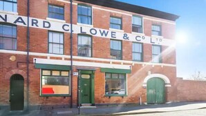 Un bâtiment en briques de deux étages, avec une enseigne portant l’inscription « NARD CLOWE & CO LTD » au-dessus de l’entrée.