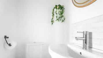 Un baño moderno con un lavamanos, un inodoro y un dispensador de papel higiénico.