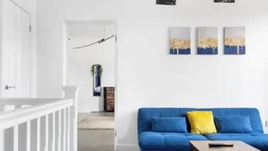 Un salon moderne avec un canapé bleu, une table basse en bois et une rambarde blanche.