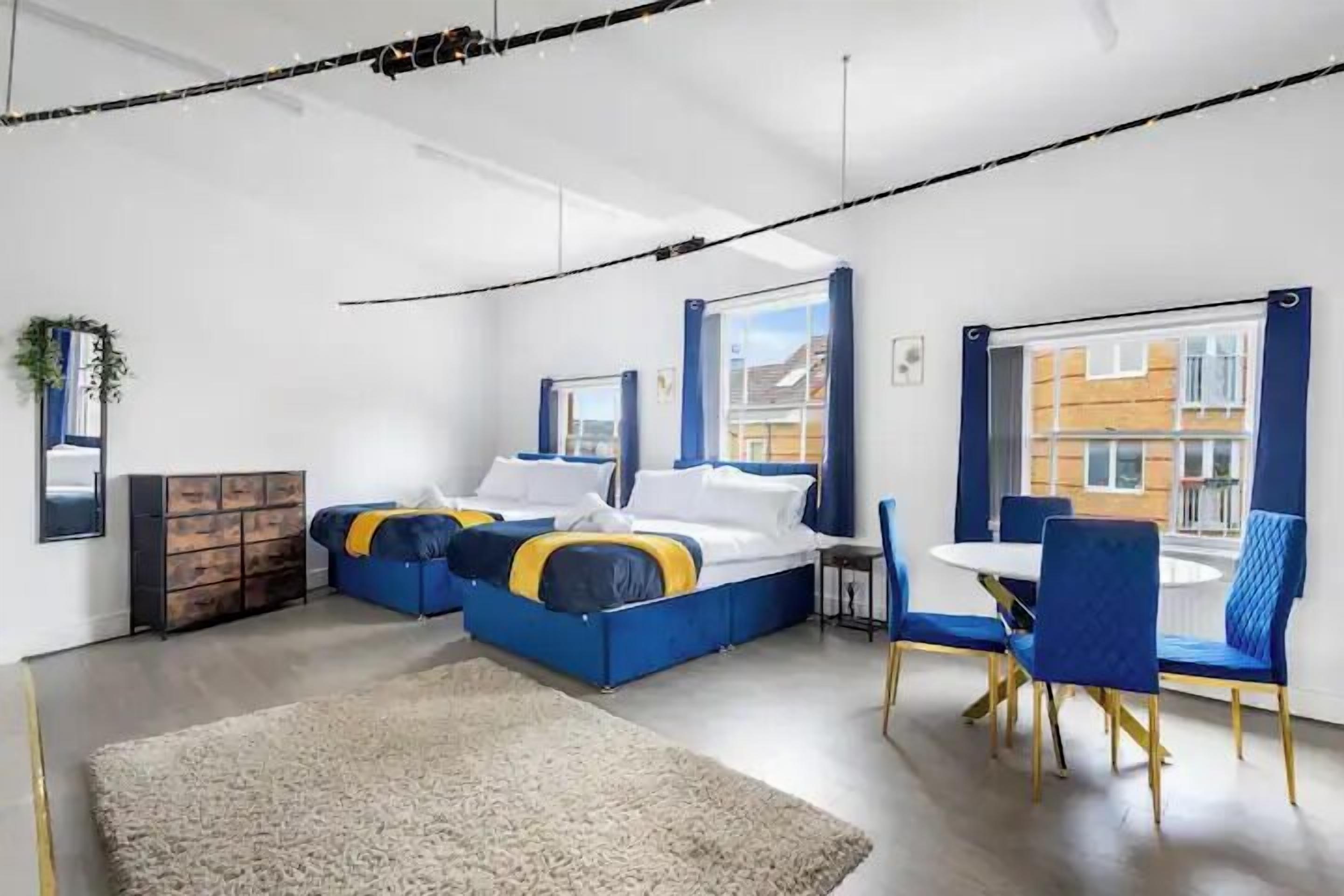 A modern bedroom with a bed, a small table, and chairs.