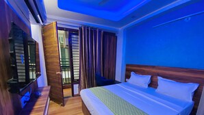 A hotel room with a bed, a desk, a chair, and a window with curtains. - Hotel Surya International (New Delhi)