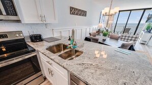 A modern kitchen with granite countertops, stainless steel appliances, and a large window overlooking the ocean. - Direct Ocean View - Exclusive Sand Beach Club 2BR (Myrtle Beach)