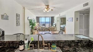 A modern kitchen with a granite countertop, stainless steel sink, and a ceiling fan. - New, Low Floor, Direct Ocean View Sands Beach Club (Myrtle Beach)