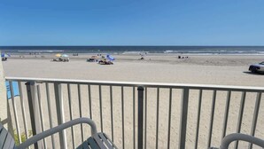 A beach view from a balcony with a railing, a sandy beach, and a clear blue sky. - New, Low Floor, Direct Ocean View Sands Beach Club (Myrtle Beach)