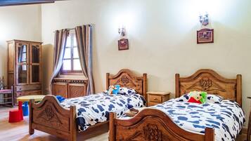 Quarto com duas camas de madeira, um armário de madeira, janela com cortinas e luminárias fixadas na parede.
