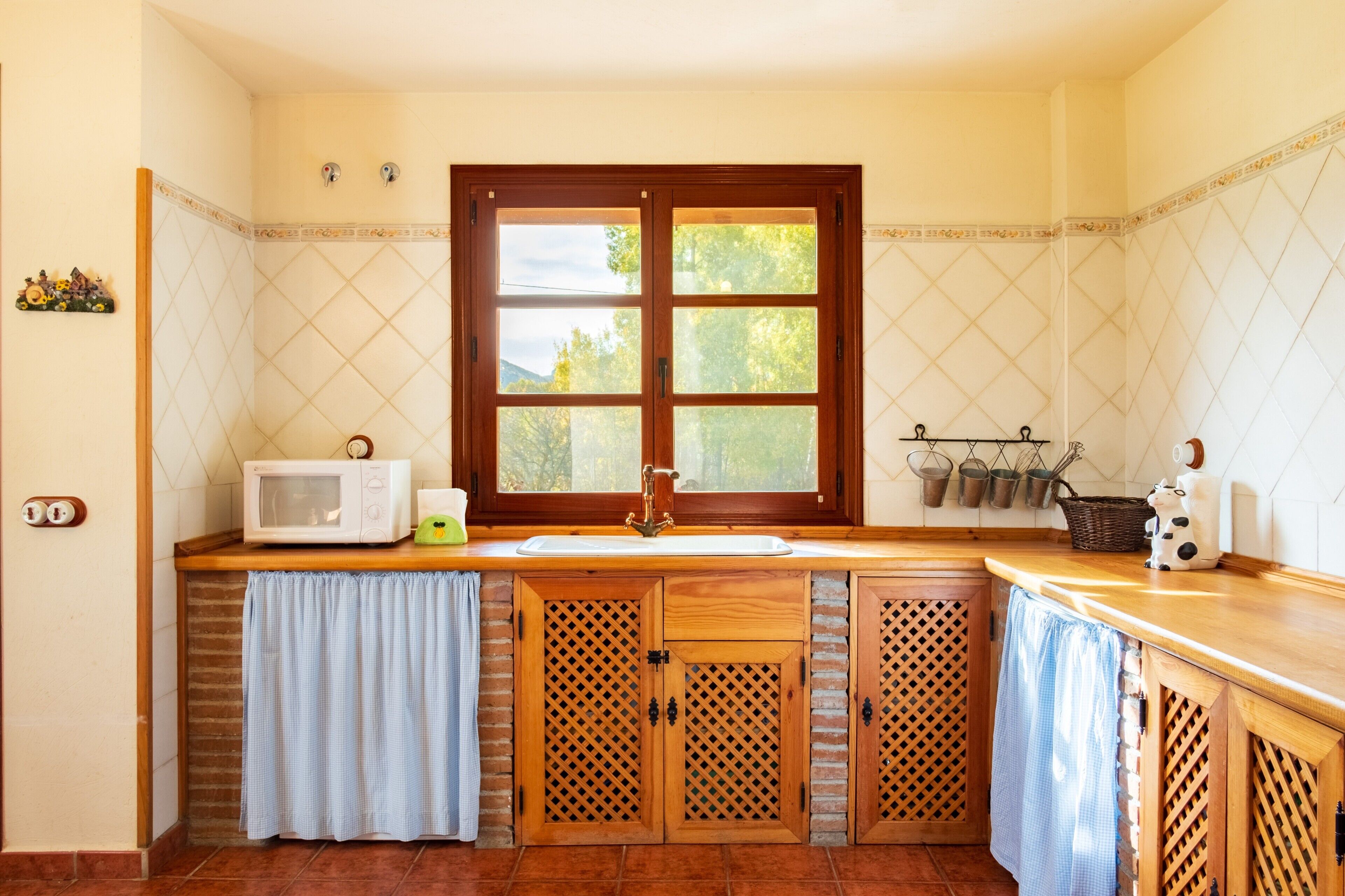 A kitchen with a wooden countertop, a window, a sink, and a microwave.
