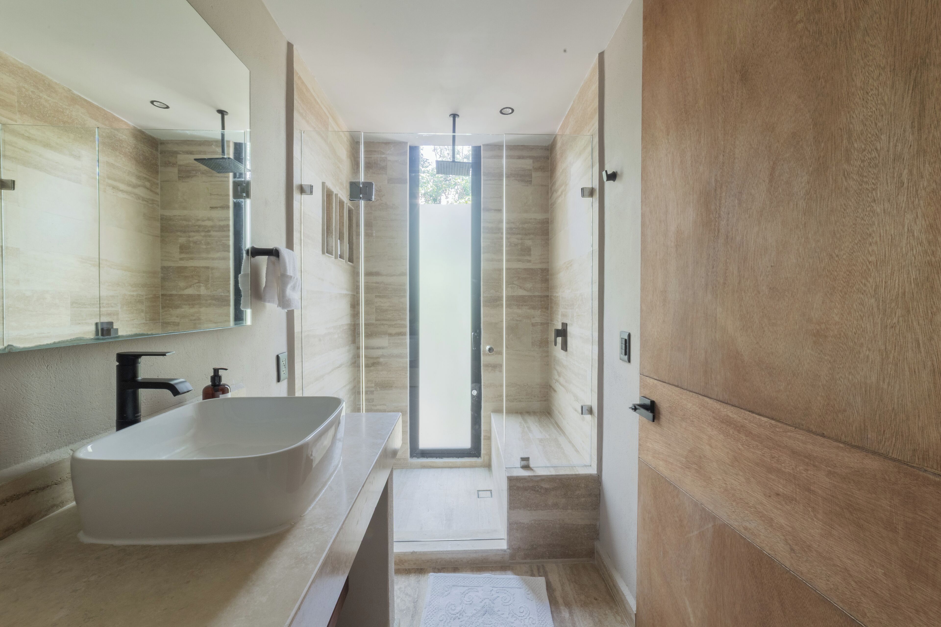 Een moderne badkamer met een vrijstaand bad, een douche met glazen wanden en een grote spiegel.
