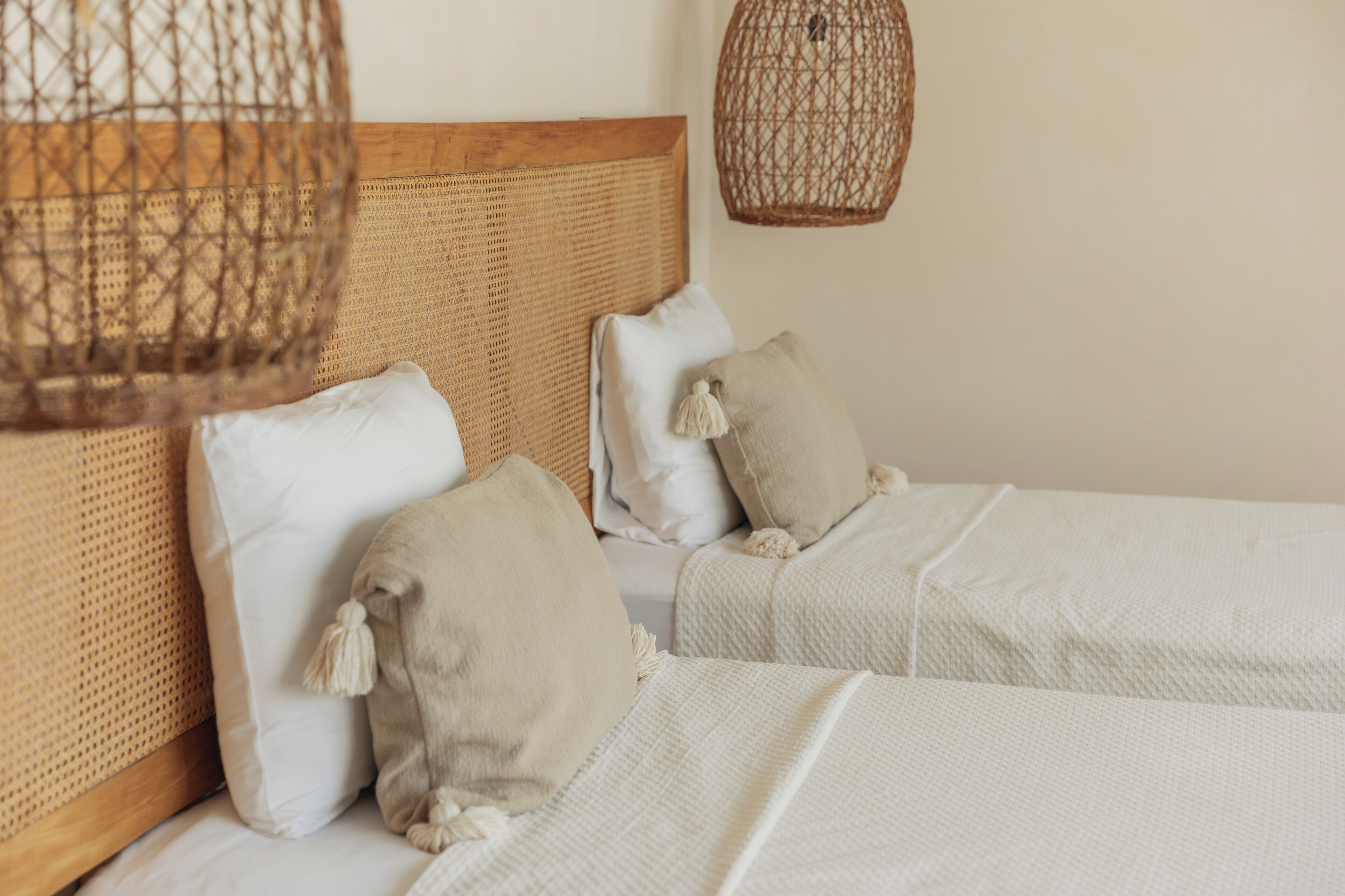 A bedroom with two beds, each with white bedding and beige pillows.