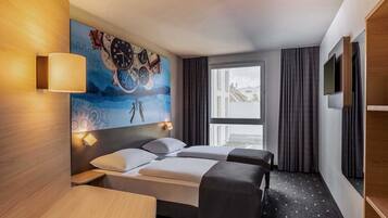 A hotel room with a bed, bedside tables, a TV, and a large window.
