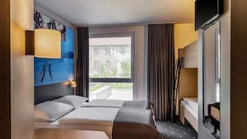 Una habitació d'hotel amb dos llits, un finestral gran, un quadre a la paret i un televisor fixat a la paret.