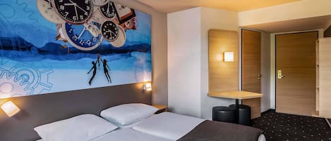 A modern hotel room with a large wall mural of clocks, a bed with white linens, a small bedside table, and a nightstand.