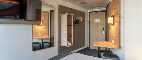 A modern hotel room with two beds, a TV, a built-in wardrobe, and a mirror.