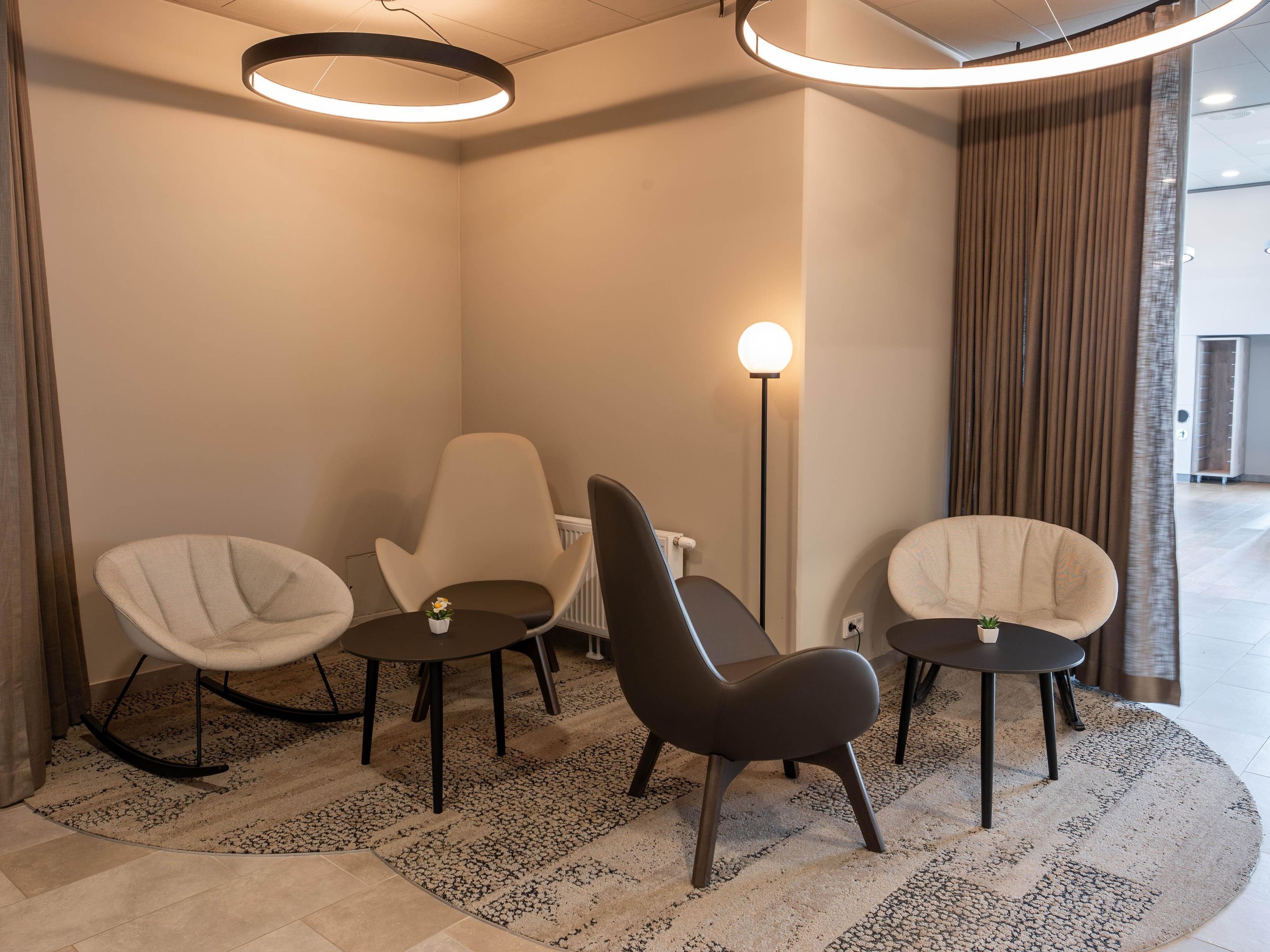 A modern room with three chairs, a floor lamp, and a circular ceiling light.