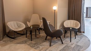 Una habitación moderna con tres sillas, una lámpara de pie y una lámpara de techo circular.