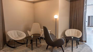 A modern room with three chairs, a floor lamp, and a circular ceiling light.