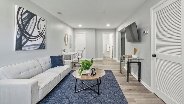 A modern living room with a white sofa, a coffee table, and a large abstract painting on the wall.
