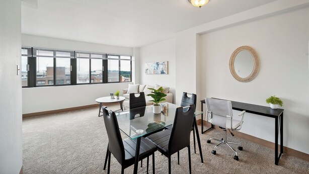 Un espace de bureau moderne avec une table en verre, des chaises noires, un bureau noir et une plante en pot.