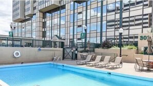 Une piscine avec des chaises longues et, en arrière-plan, un bâtiment doté de grandes fenêtres.