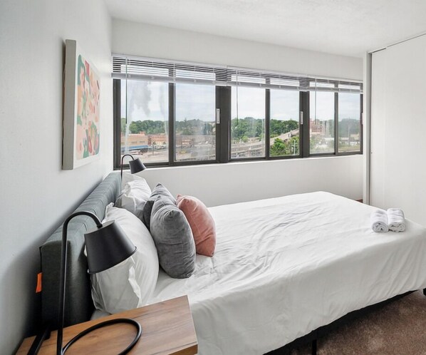 A modern hotel room with a large bed, a desk, and a window with blinds. - PP 501 Harrisburg Gem 2br, Pool, Parking (Harrisburg)