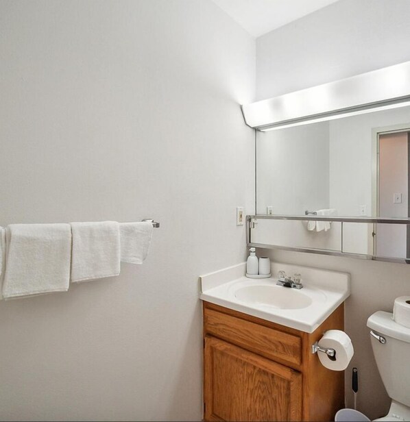 Une salle de bain avec un lavabo blanc, un meuble en bois et un miroir au-dessus du lavabo.
