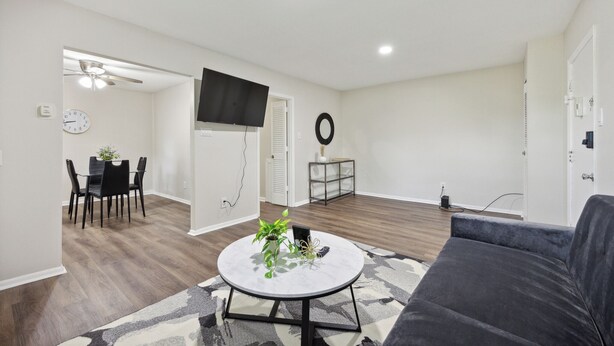 A modern living room with a round coffee table, a gray sofa, and a dining area with a table and chairs. - Pine Brook 1202 I Pool Gym I Free Parking ! (Newark)