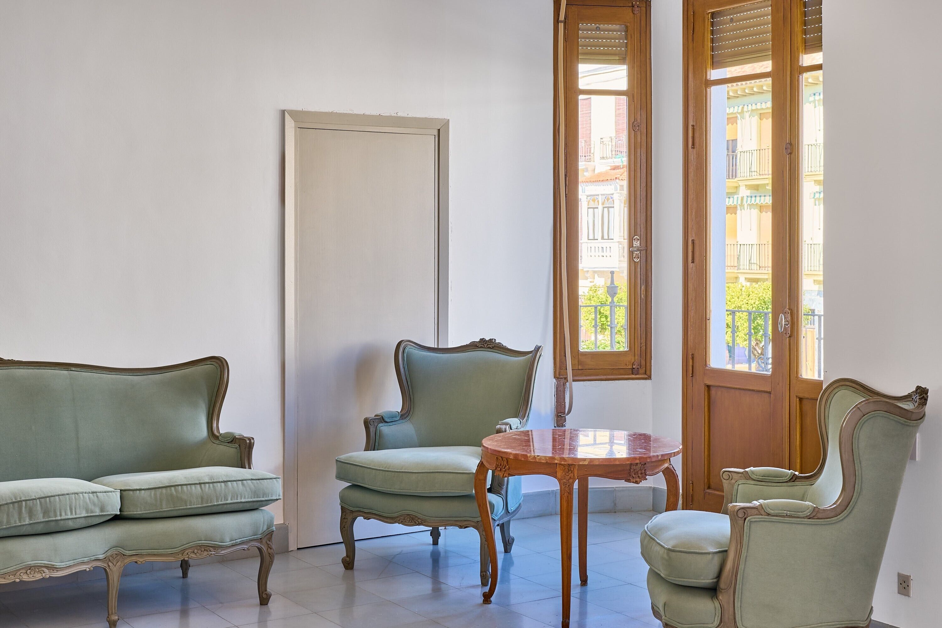 Una habitación con un sofá verde, una mesa de madera y una silla.
