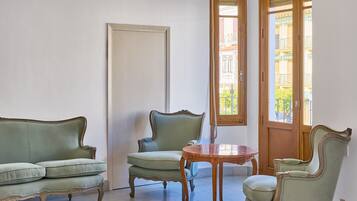 Una habitación con un sofá verde, una mesa de madera y una silla.