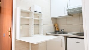 Una cocina con armarios blancos, estante empotrado, lavamanos y lavavajillas Benavent.