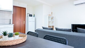 A modern living room with a grey sofa, a dining table with a woven placemat, and a TV on the wall. - Cozy Apartment in Vallecas (Madrid)