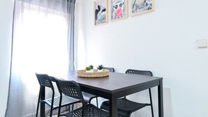 A dining area with a table and four chairs, a window with a sheer curtain, and three framed animal pictures on the wall. - Cozy Apartment in Vallecas (Madrid)
