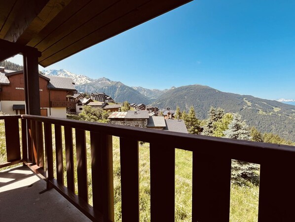 A wooden balcony overlooking a mountainous landscape with traditional buildings.