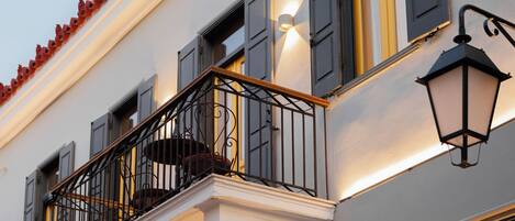 Een gevel met een balkon, een verlichte wandlamp en een bord met de naam 'T. & K. PAPANIKOS'.