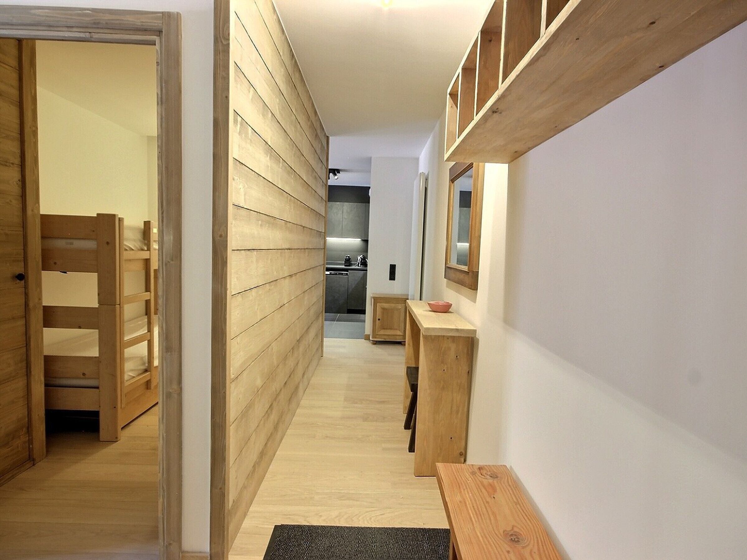 A hallway with wooden walls and flooring, a wooden bench, and a small table with a bowl.
