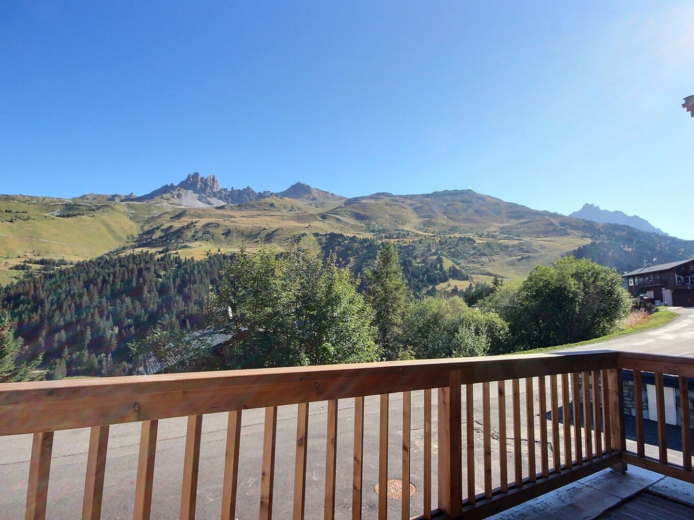 A wooden deck with a view of a mountain range and forested hills.