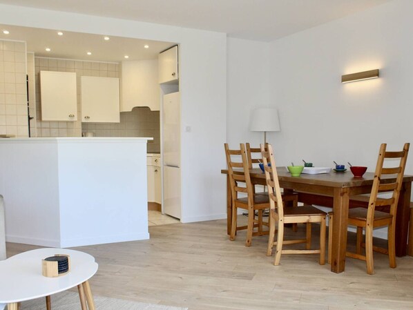 A modern kitchen with white cabinets and a dining area with wooden chairs and a table.
