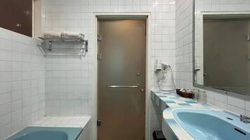 Un baño con bañera, lavamanos, espejo, toallero y una puerta.