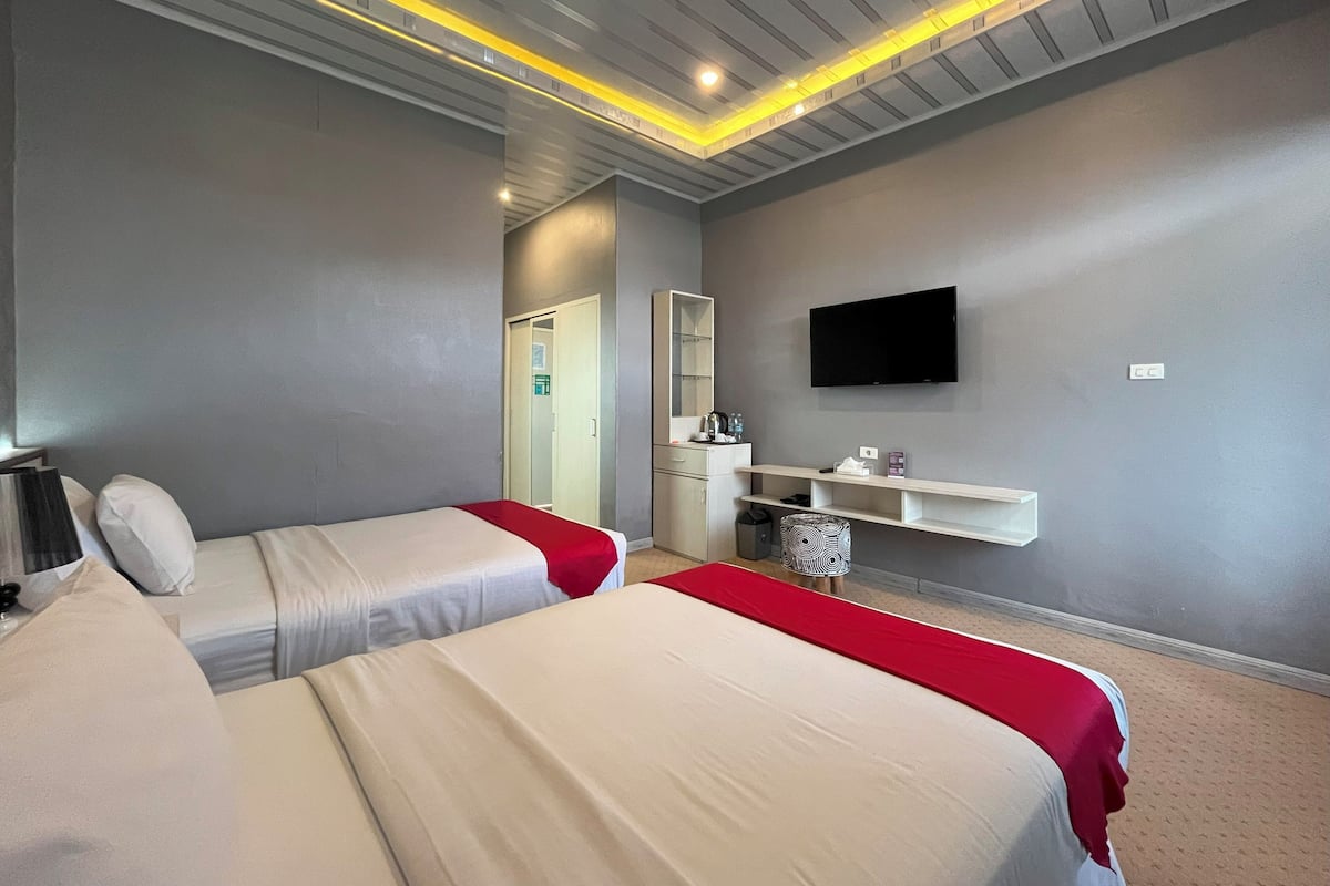 Habitación de hotel con dos camas, televisión, escritorio y espejo.