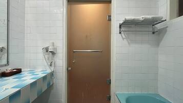 Ein Badezimmer mit einer braunen Tür, einer blau karierten Arbeitsplatte, einer weißen Fliesenwand, einer weißen Badewanne und einem Handtuchhalter mit Handtüchern.