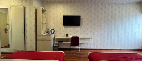 A hotel room with two beds, a desk with a chair, a television, and a wardrobe.